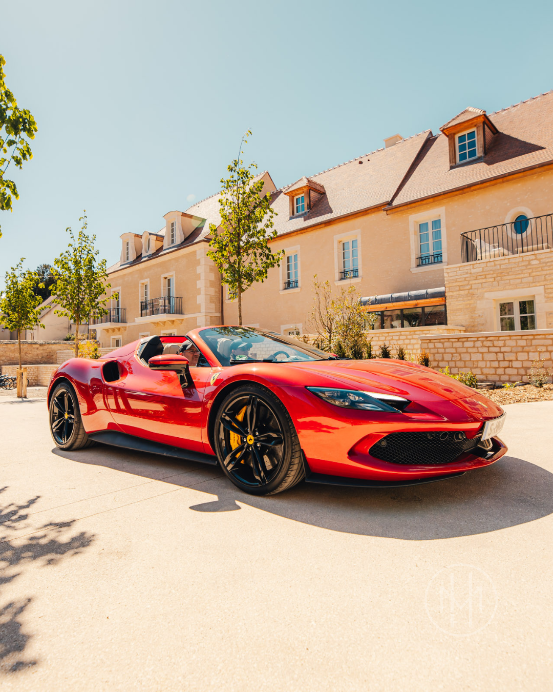 Red Ferrari supercar parked in front of a stone hotel on the drive between the Riviera and the Alps