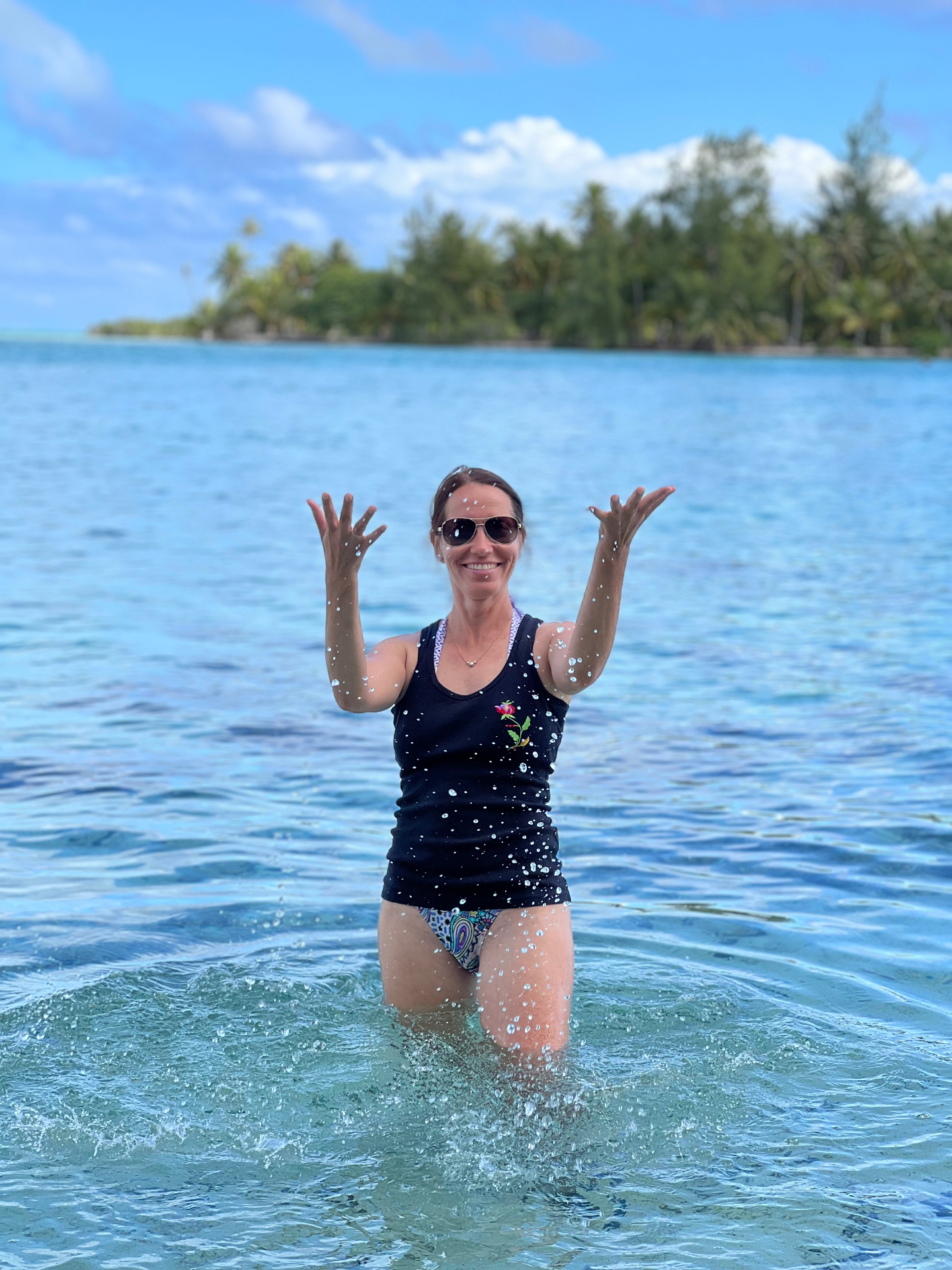Heni, luxury travel advisor, playing in the lagoon shallows near a private motu in Tahaa, French Polynesia
